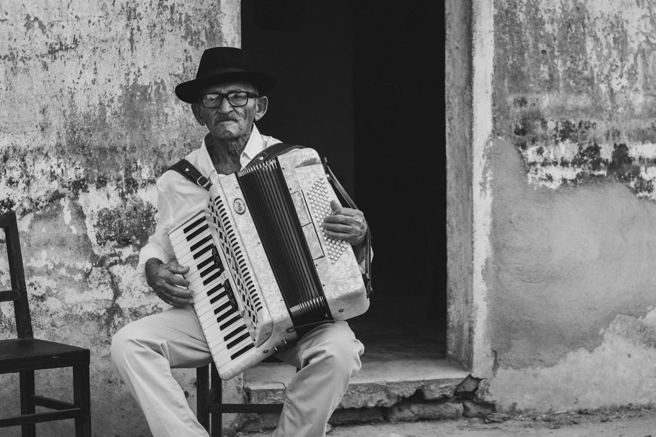 A senior man playing an accordion outside a building in Paulista, Brazil.